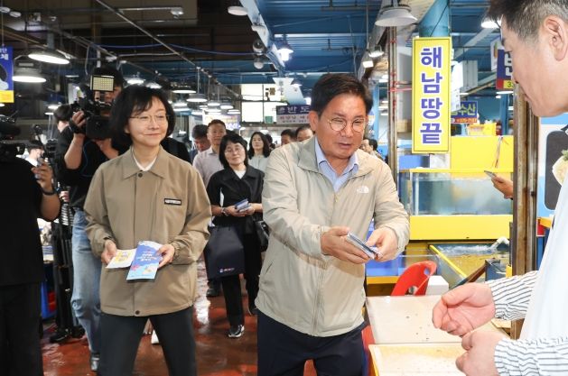 12일 박강수 구청장(가운데)이 마포농수산물 시장 판매자에게 식중독 예방 홍보물을 건네며 인사하고 있다.
