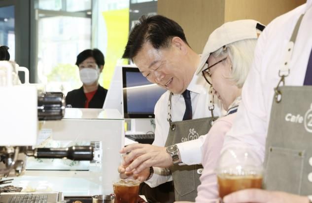 박승원 광명시장이 지난해 4월 광명시인생플러스센터 1층에 문을 연‘카페(CAFE)-20'에서 시니어 바리스타와 함께 커피를 내리고 있다.