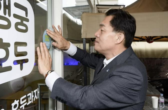 이재준 수원시장이 행궁동에 한 민생회복소비쿠폰 사용처에 스티커를 부착하고 있다.