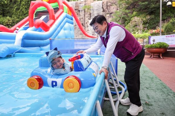 배봉산 물놀이장 안전점검 나선 이필형 동대문구청장이 아이와 함께 물장난을 치고있다