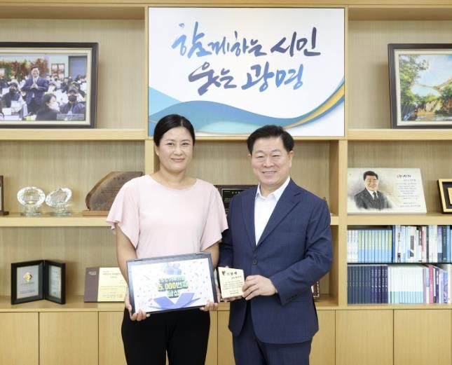 박승원 광명시장(사진 오른쪽)이 21일 오전 시장실에서 1만 5천 번째 ‘1.5℃ 기후의병’ 가입자 최 모 씨(사진 왼쪽)를 만나 기념패를 전달하고 기념사진을 촬영하고 있다.