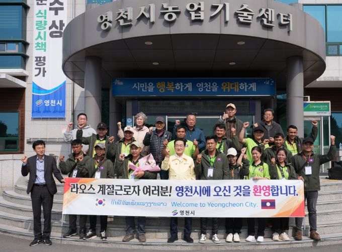 12일 농업기술센터 전정에서 1차로 입국한 라오스 계절근로자 16명의 환영식을 열고, 기념촬영을 하고 있다.
