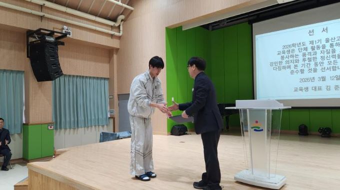 울산고 학생 대표가 12일 학생교육원에서 '행복 어울림 교육' 활동에 앞서 선서를 하고 이재근 원장과 악수하고 있다